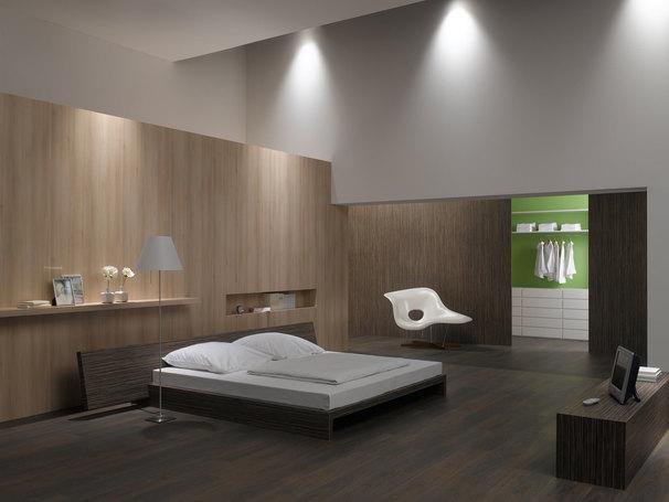 Schlafzimmerimpression mit Holzverkleidung an Wand Schlafzimmerimpression von Bett, Nachtisch und Sideboard mit Holzverkleidung an Wand und indirektert Beleuchtung