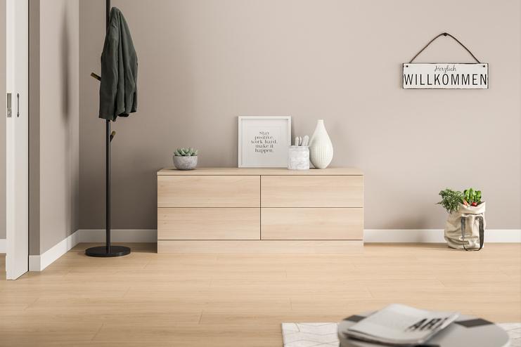 Maßgefertigte, helle Kommode im modernen Eingangsbereich. Eine schlichte, maßgeschneiderte Kommode in hellem Holzdekor mit glatten Fronten, harmonisch integriert in den einladenden Eingangsbereich eines Hauses.